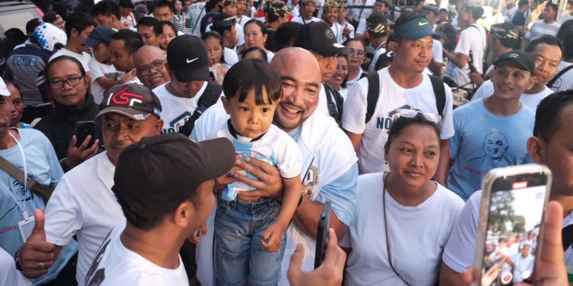 De Gadjah menggendong seorang anak saat Jalan Sehat Relawan De Gadjah di Buleleng.