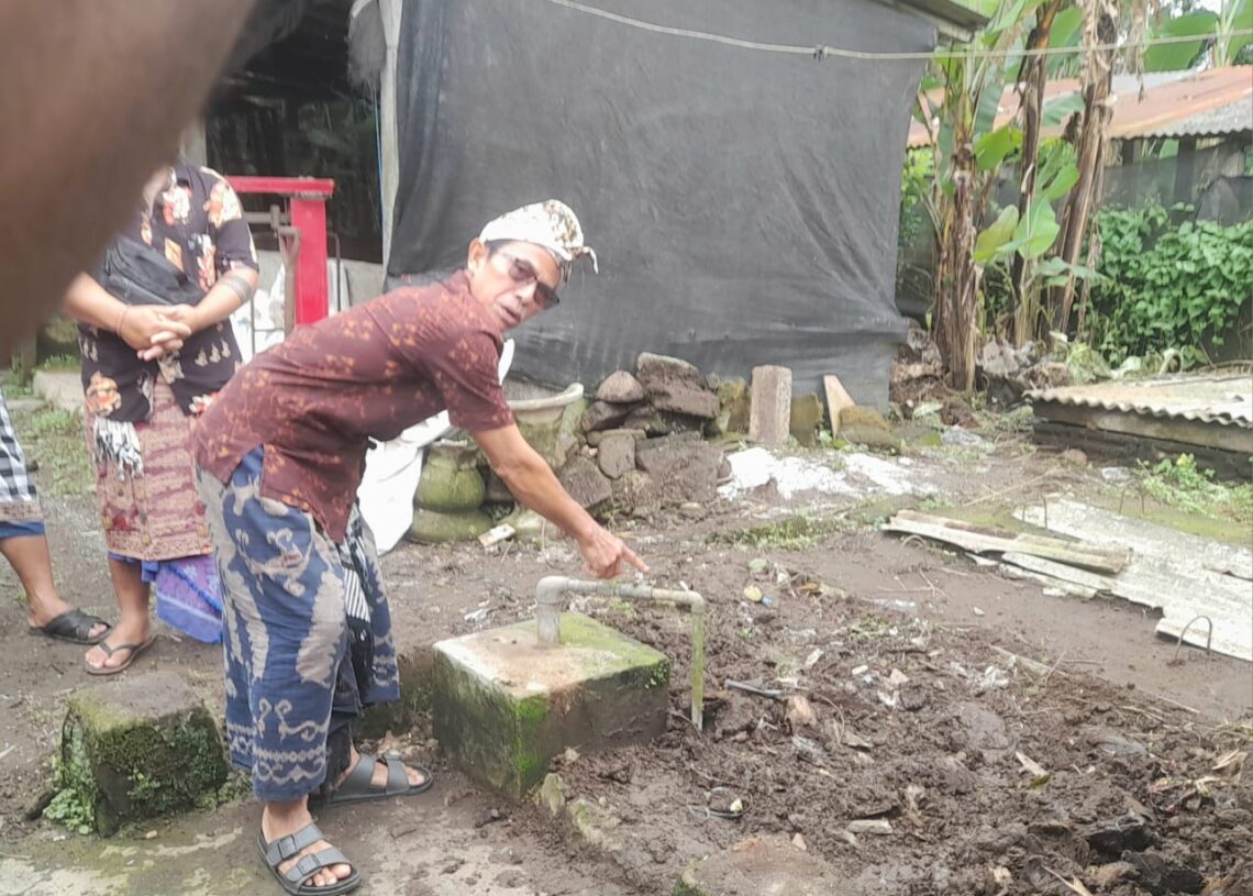 Ketut Sepot saat menunjuk tangki tertutup penampung kotoran babi yang dijadikan biogas. -Balitopik.com