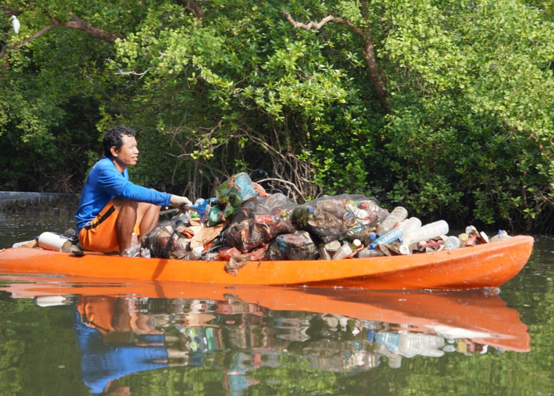 Potret seorang warga sedang mengangkut sampah plastik dari kawasan Mangrove Batu Lumbang, Denpasar. -BALITOPIK.COM