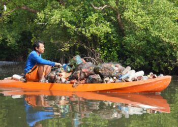 Potret seorang warga sedang mengangkut sampah plastik dari kawasan Mangrove Batu Lumbang, Denpasar. -BALITOPIK.COM