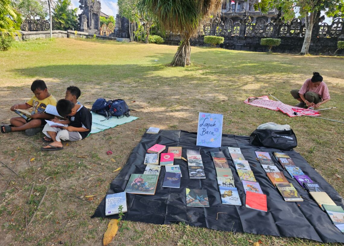 Potret sejumlah anak-anak membaca buku yang dipajang oleh AJI Denpasar di lapangan Renon. -IST