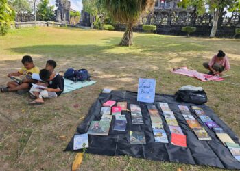 Potret sejumlah anak-anak membaca buku yang dipajang oleh AJI Denpasar di lapangan Renon. -IST